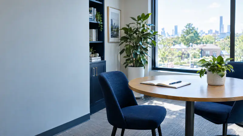Welcoming small office with a round meeting table, two chairs and a notebook in soft window light