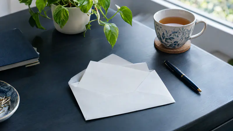 Opened envelope and letter on a calm, tidy desk with a pen and cup of tea