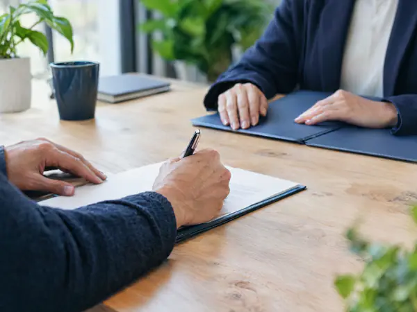 Business owner signing a document across a meeting table during a tax review
